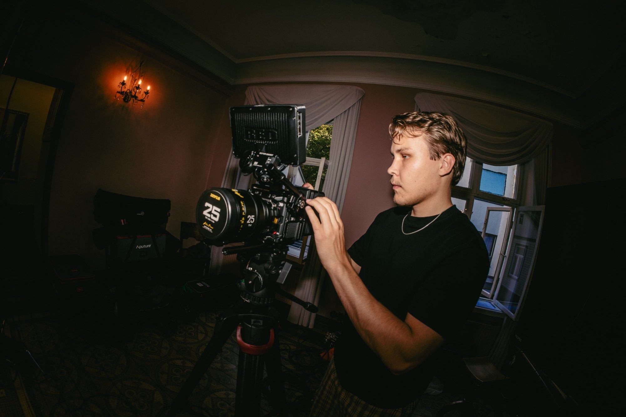 Lucas Ekblad framing a shot on a RED cinema camera with a 25 mm lens, in a room with candle sconces.